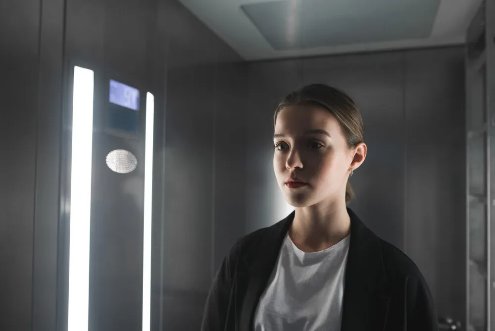 portret poważnej dziewczyny w kurtce, patrzącej w stronę drzwi.