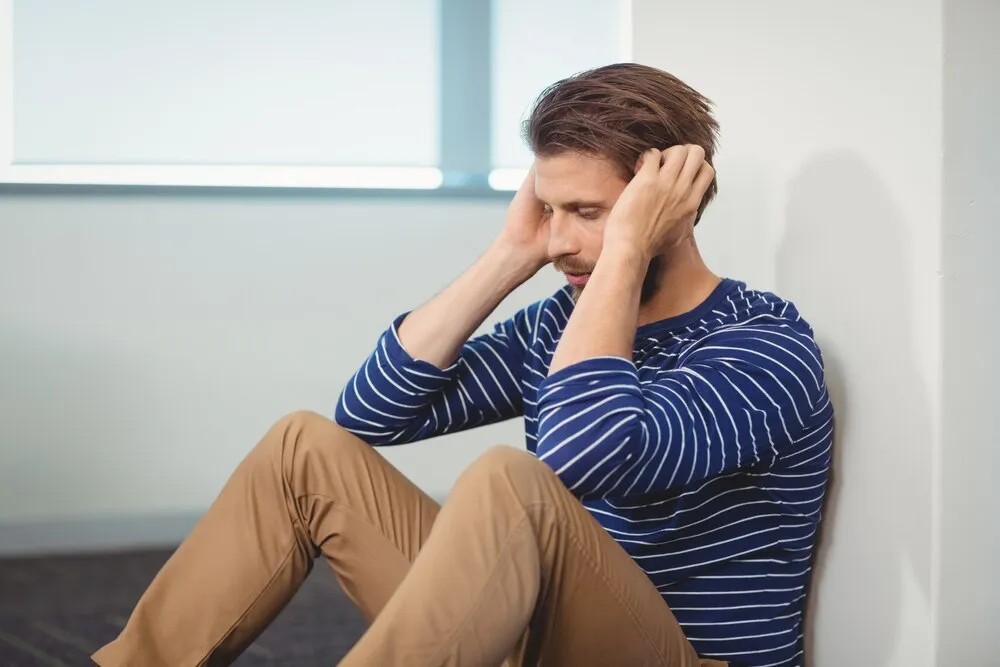 smutny dyrektor siedzący pod ścianą