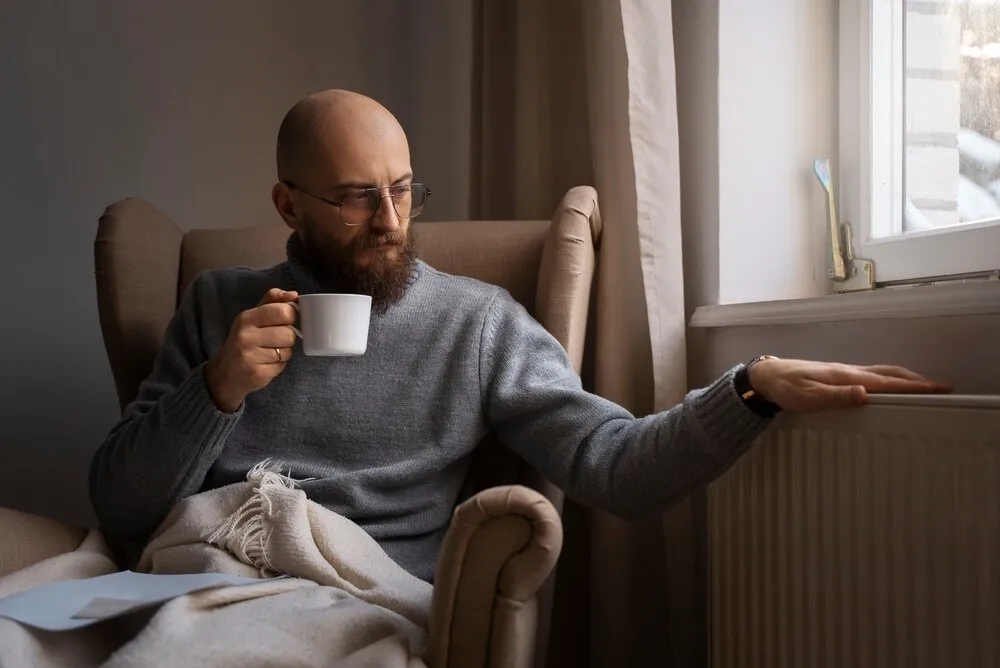 mężczyzna próbujący się ogrzać podczas kryzysu energetycznego
