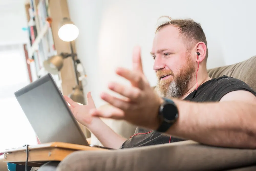 Mężczyzna gestykulujący podczas korzystania z laptopa w domu