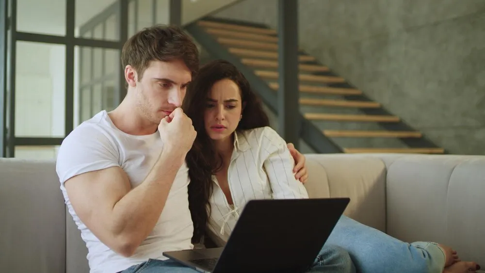 Portret młodej pary małżeńskiej oglądającej straszny film na laptopie